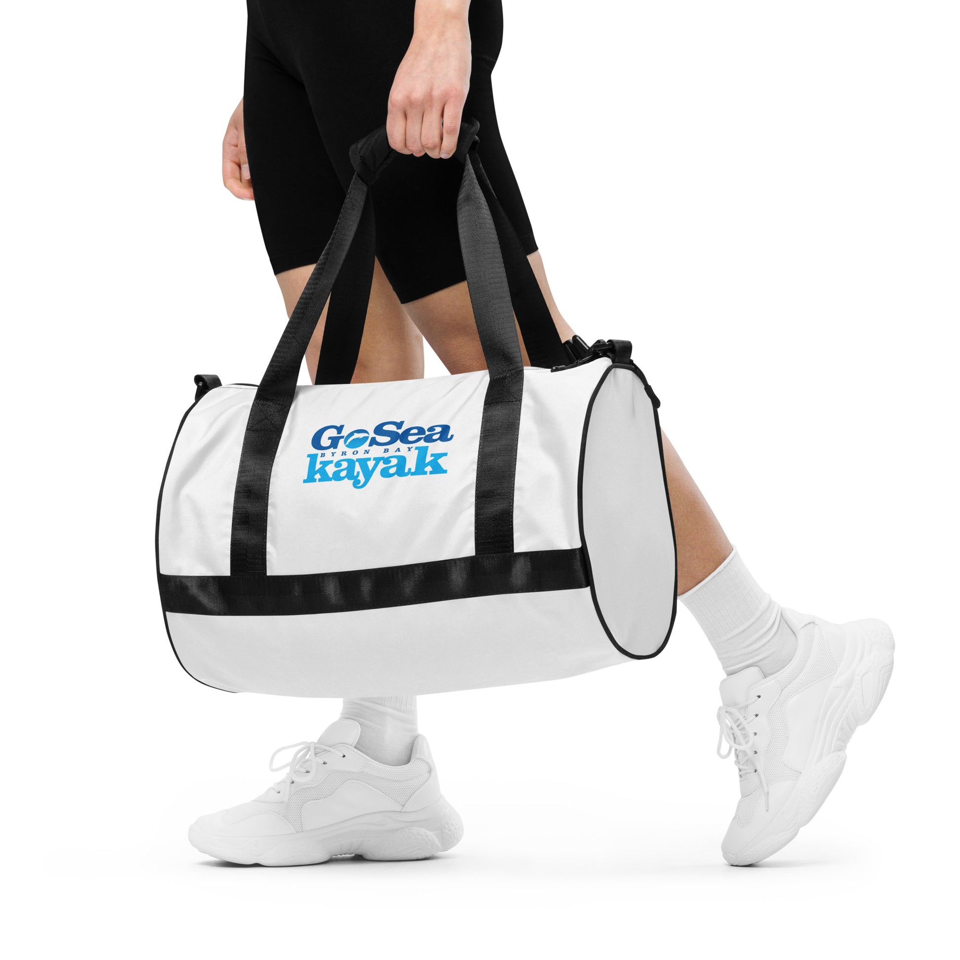  Gym Bag - White with black trim/detail - Side view, being held by man walking - With Go Sea Kayak Byron Bay logo on both sides - Genuine Byron Bay Merchandise | Produced by Go Sea Kayak Byron Bay 
