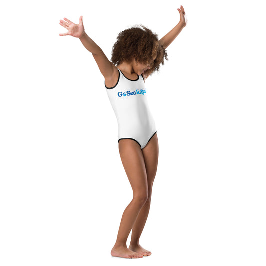  Girls One-Piece Swimsuit - White with black trim/detail - Front view being warn girl with her hands in the air - With Go Sea Kayak Byron Bay logo on front - Genuine Byron Bay Merchandise | Produced by Go Sea Kayak Byron Bay 
