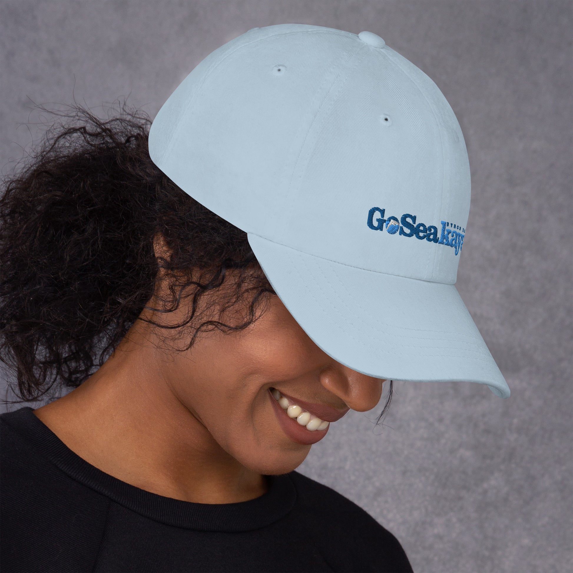  Unisex Cap - Light Blue - Woman wearing cap looking down - Go Sea Kayak logo on front  - Genuine Byron Bay Merchandise | Produced by Go Sea Kayak Byron Bay