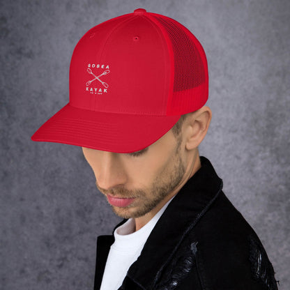  Trucker Cap - Red - side view - being warn by man with his head down - Crossed Paddles Go Sea Kayak Crew logo in white on front - Genuine Byron Bay Merchandise | Produced by Go Sea Kayak Byron Bay 