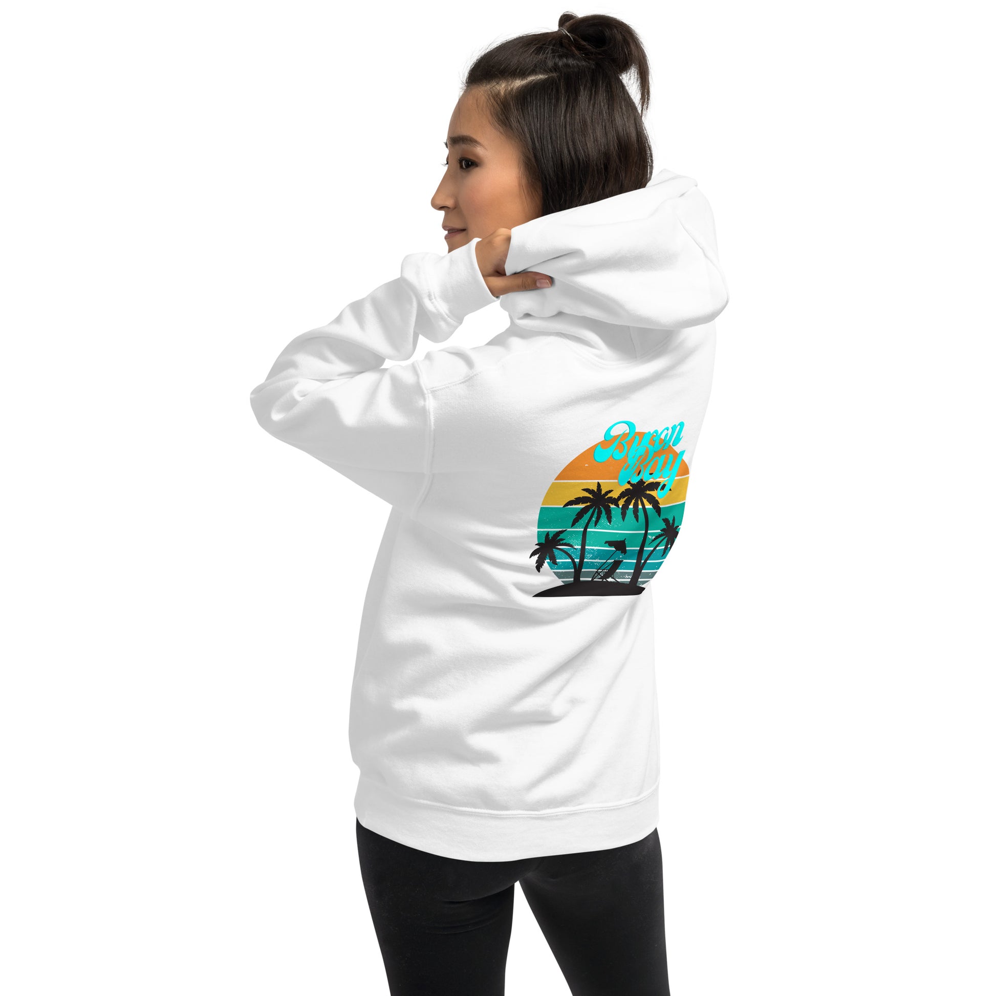  Unisex Hoodie - White - Back view being warn by woman pulling the hood on whilst looking over her shoulder - Byron Bay design on back, plain front with pouch pocket - Genuine Byron Bay Merchandise | Produced by Go Sea Kayak Byron Bay 