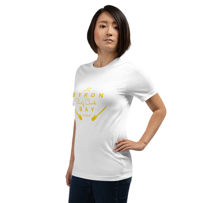  Unisex T-Shirt - White - side view, on woman standing with on hand on hip - yellow Byron Bay Surf Club logo on front - Genuine Byron Bay Merchandise | Produced by Go Sea Kayak Byron Bay 