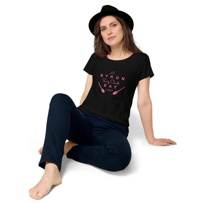  Women’s Round Neck Tee - Black - Front view, woman on floor knee up resting back on her hands - pink Byron Bay Surf Club logo on front - Genuine Byron Bay Merchandise | Produced by Go Sea Kayak Byron Bay 
