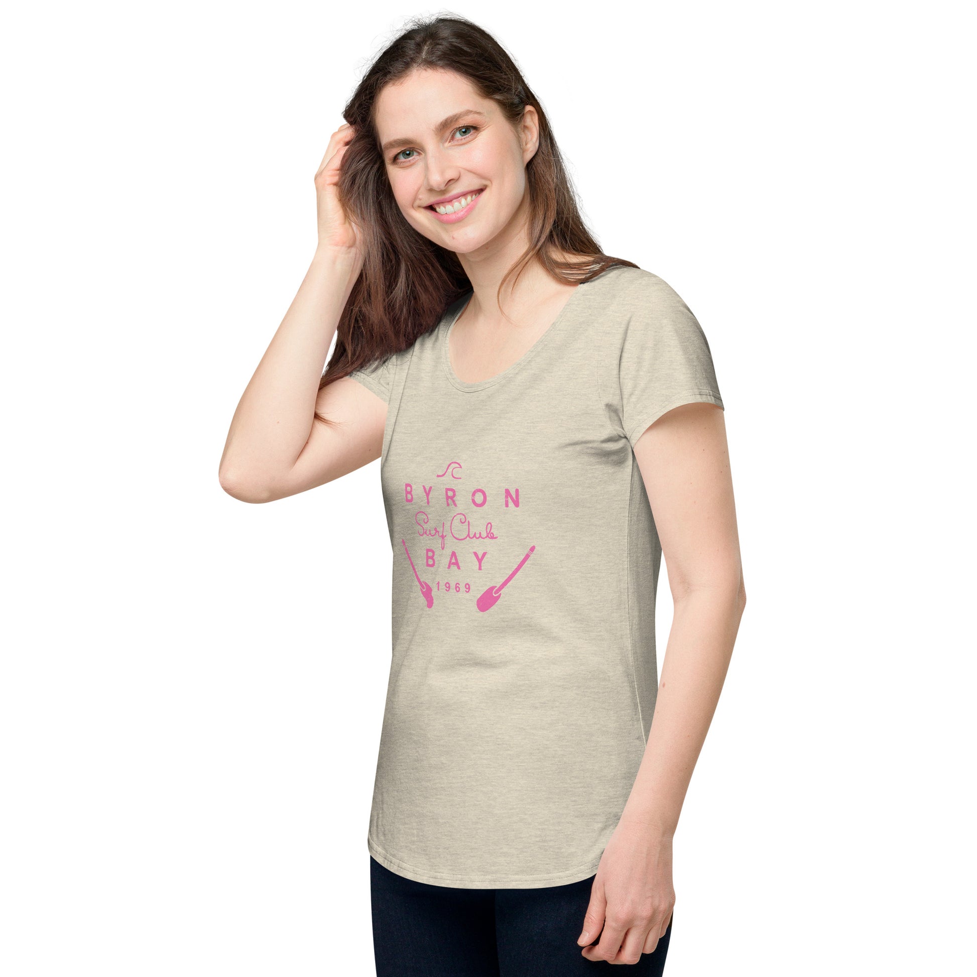  Women’s Round Neck Tee - Oatmeal - side view, on woman standing with one hand touching hair - pink Byron Bay Surf Club logo on front - Genuine Byron Bay Merchandise | Produced by Go Sea Kayak Byron Bay 