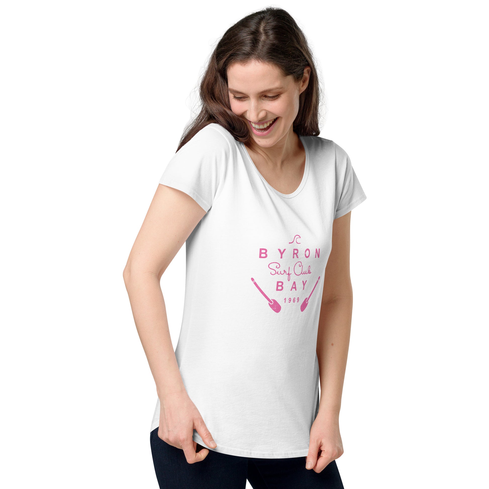  Women’s Round Neck Tee - White - Front view, being warn by woman holding the bottom of the tee - pink Byron Bay Surf Club logo on front - Genuine Byron Bay Merchandise | Produced by Go Sea Kayak Byron Bay 