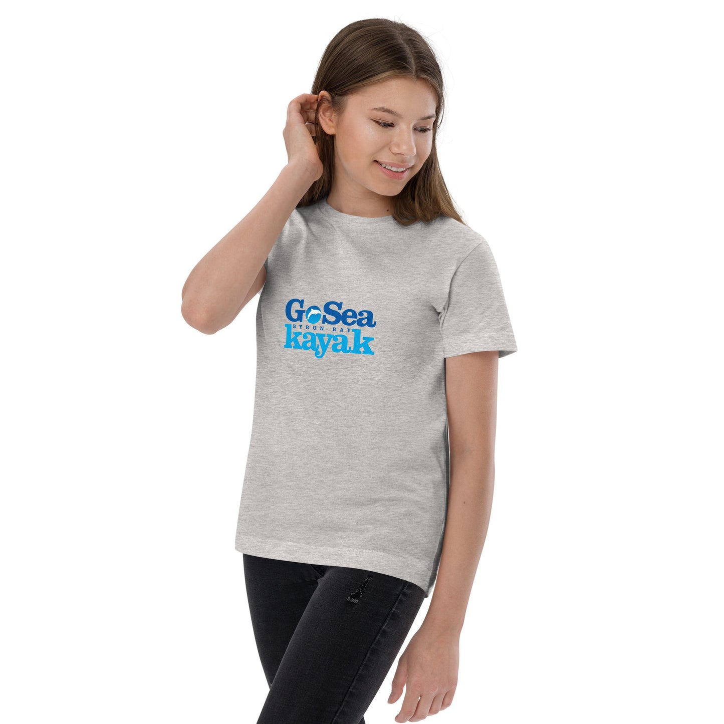  Kids T-Shirt - Natural / Heather colour - Front view, being warn on a girl standing with one arm by her side the other pushing her hair back - Go Sea Kayak Byron Bay logo on front - Genuine Byron Bay Merchandise | Produced by Go Sea Kayak Byron Bay 