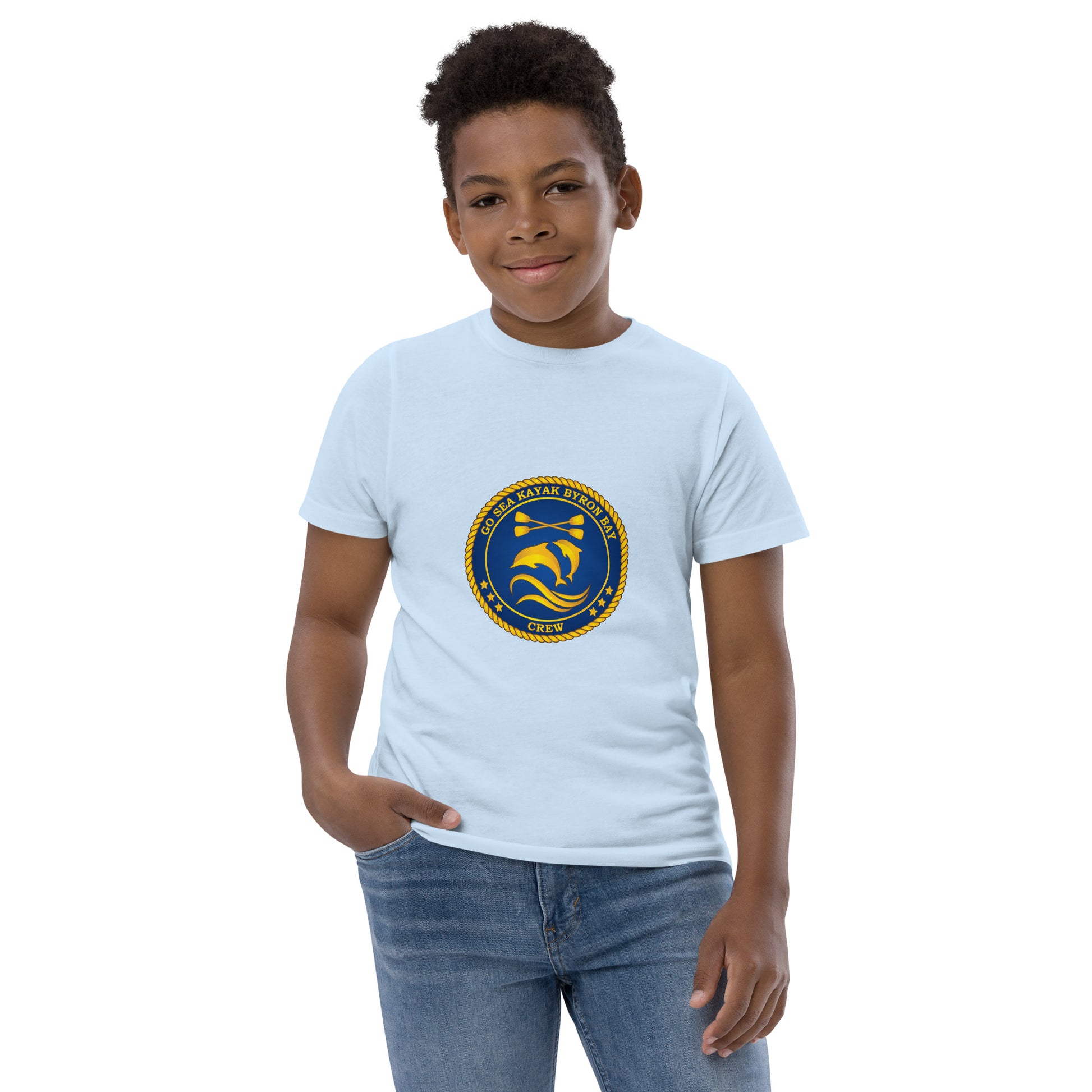  Kids T-Shirt - Light Blue - Front view, being warn on boy standing with a hand in his pocket - Go Sea Kayak Byron Bay Crew (issue 2018-2019) logo on front - Genuine Byron Bay Merchandise | Produced by Go Sea Kayak Byron Bay 