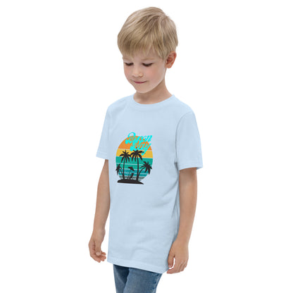  Kids T-Shirt - Light Blue - Side view, being warn on boy standing with a hand in his pocket - Byron Bay design on front - Genuine Byron Bay Merchandise | Produced by Go Sea Kayak Byron Bay 